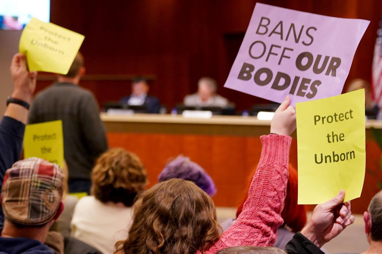Meeting attendees hold up signs as Mason city council passed an ordinance criminalizing abortions within the city limits, by a vote of four votes to three, Monday, Oct. 25, 2021, in Mason. It failed to pass as an emergency, meaning it won't go into effect for 30 days. 