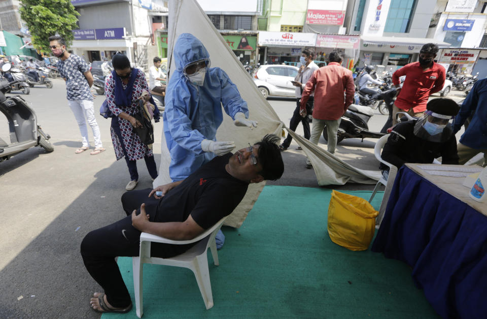 A health worker takes a nasal swab sample to test for COVID-19 test at a facility erected to screen people in Ahmedabad, India, Tuesday, Sept. 22, 2020. The nation of 1.3 billion people is expected to become the coronavirus pandemic's worst-hit country within weeks, surpassing the United States. (AP Photo/Ajit Solanki)