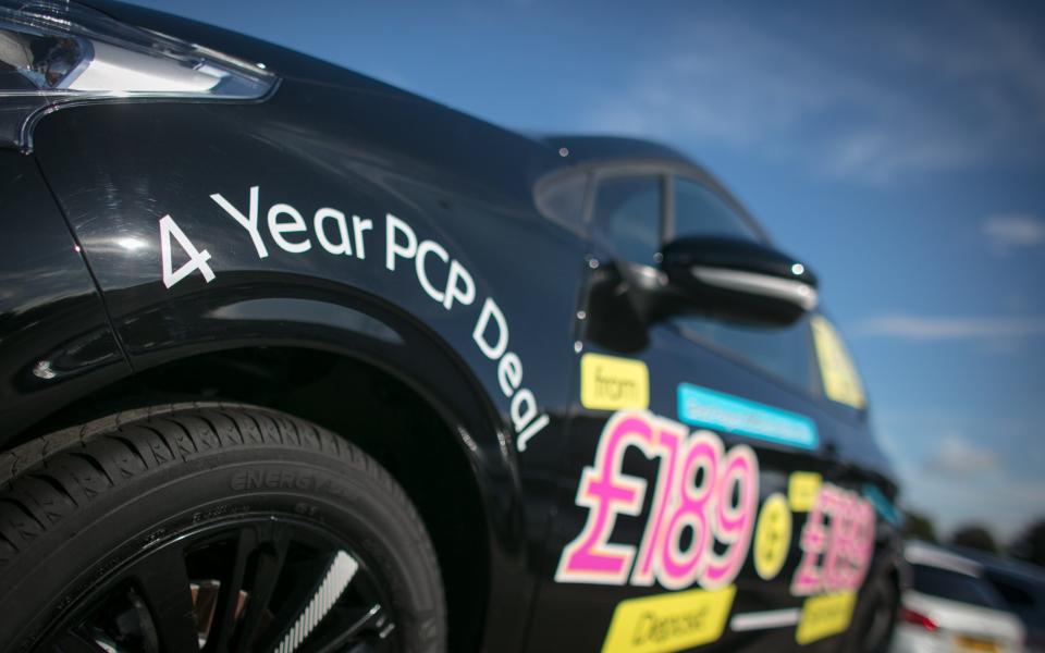 nearly new cars are displayed for sale on a forecourt of a car dealership