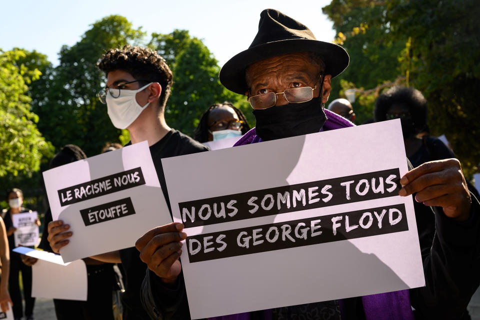 Protesters hold placards reading 