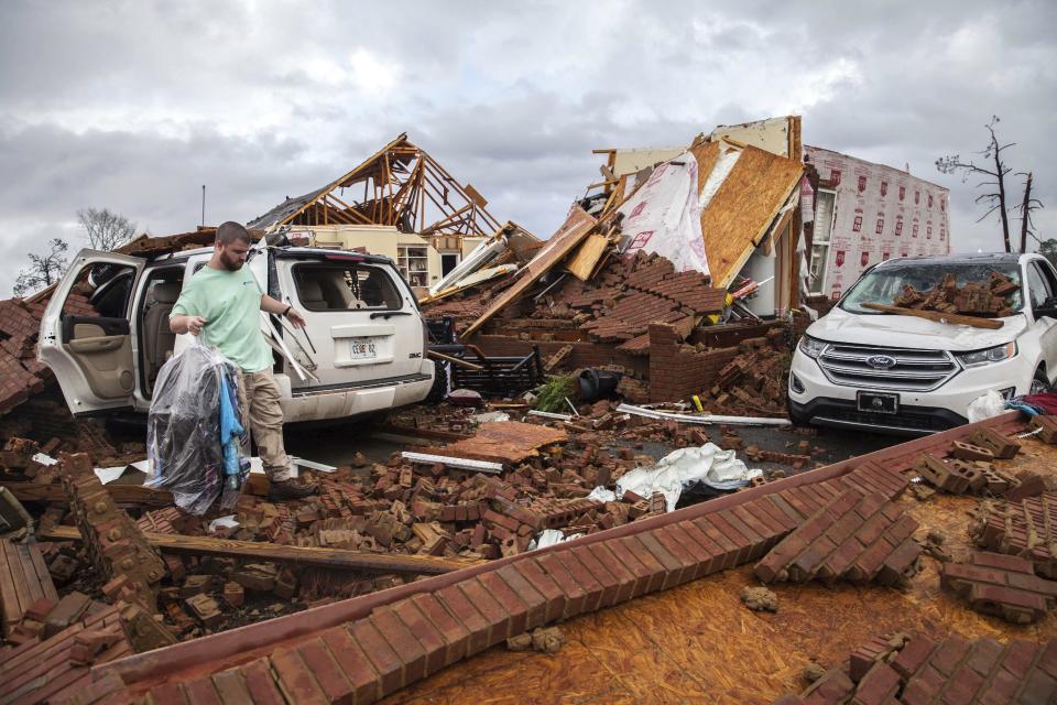 Ren, who only gave his first name, retrieves clothing from a damaged car parked at a home that was hit by a tornado, Sunday, Jan. 22, 2017, in Adel, Ga. (AP Photo/Branden Camp)