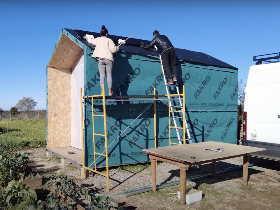 Romero and Diaz installing the cabin's black facade.