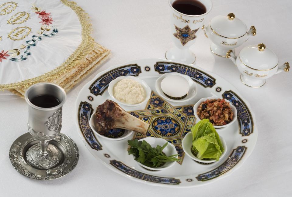 seder table including seder plate with 6 indentions holding symbols of passover such as bitter herbs, bone, egg, charoset
