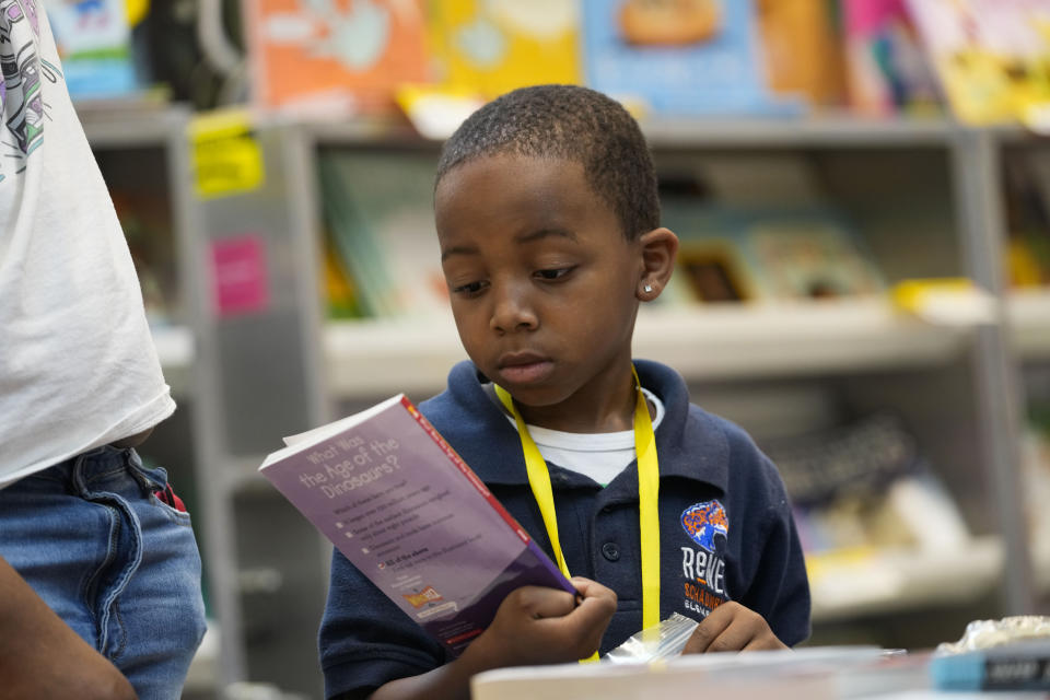 First grader Anthony Johnson, 7, looks at a book during class at Schaumburg Elementary, part of the ReNEW charter network, in New Orleans, Wednesday, April 19, 2023. (AP Photo/Gerald Herbert)