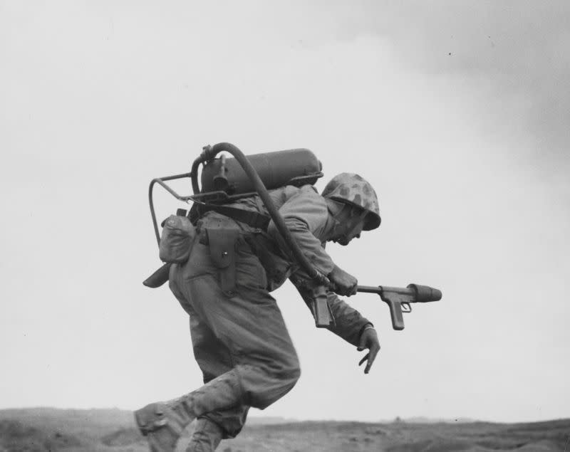 A U.S. Marine flamethrower operator with K Company goes over the top to assault a Japanese pillbox on Iwo Jima's Airfield Number Two