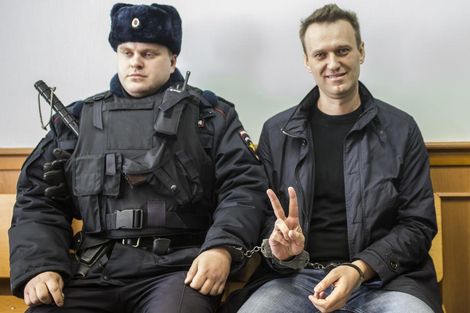 FILE - In this file photo taken on Thursday, March 30, 2017, Russian opposition leader Alexei Navalny, right, shows a V-sign for the media in court in Moscow, Russia. As Russia's most determined and durable opposition figure, Alexei Navalny has employed an astute understanding of social media and an accountant's ability to wade through financial data, a knack for sardonic humor and fierce resolve in the face of repeated threats. Now, his family, friends and supporters have a new reason to worry. The 44-year-old opposition remained in grave condition in a Siberian hospital Friday more than a day after he became ill on a flight back to Moscow and fell into a coma. His allies suspect he drank poisoned tea before boarding the plane. (AP Photo/Evgeny Feldman, File)