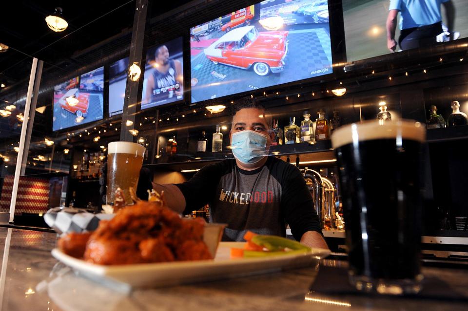 In this 2021 file photo, bartender Josue Rosa is pictured with chicken wings and beer at SKYBOKX 109 Sports Bar and Grill in Natick.