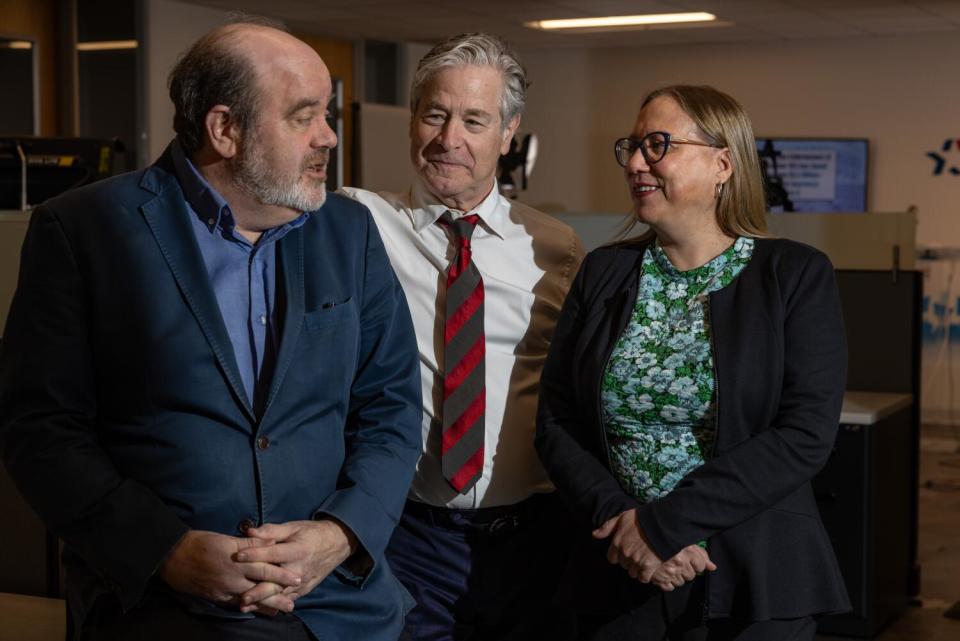 Two men and a woman stand in an office