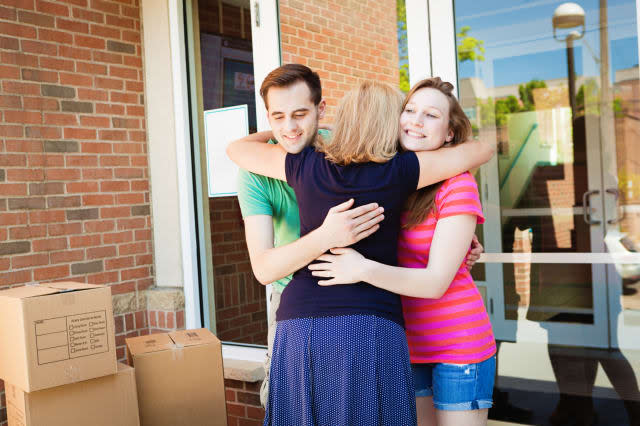 Family hugging and saying goodbye to college students moving dormitory in a university campus. Mother emotional goodbye to colle