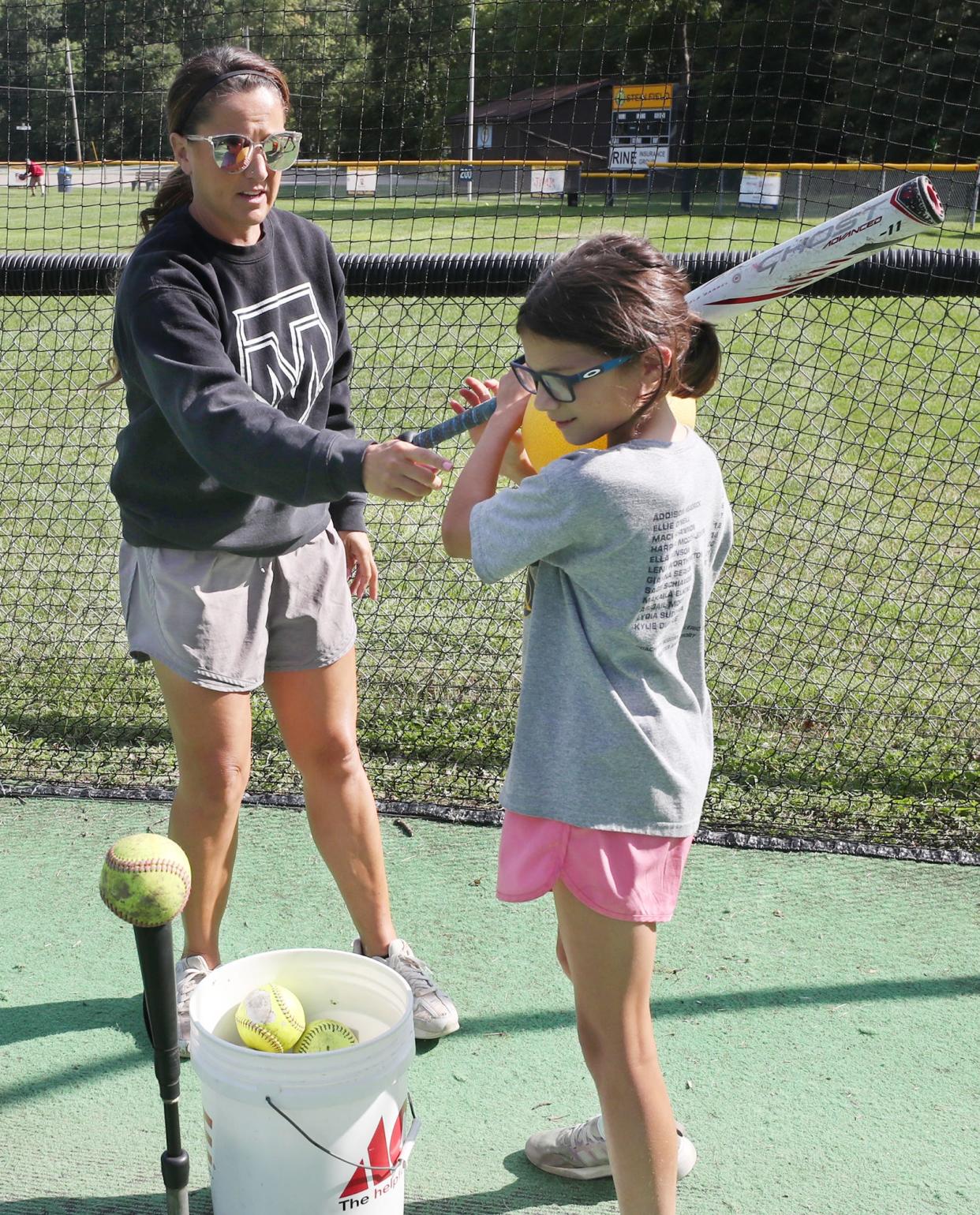 Tracee McCoy-Jenkins, an Ellet High School, University of Akron and Akron Racers softball legend, works with her student, Lydia, 10, in the batting cages at Stein Field at Indian Hills Park in Tallmadge on Aug. 22.