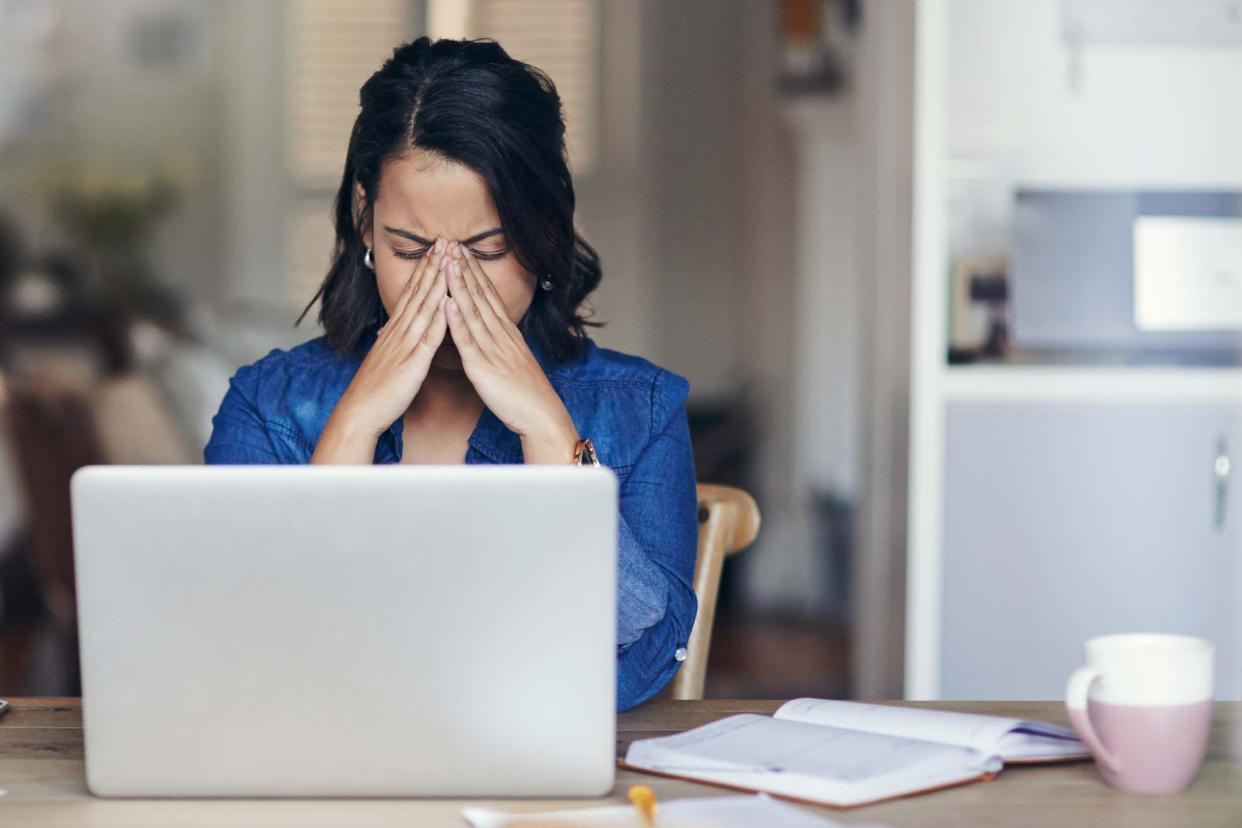 woman looking stressed while using a laptop to work from home