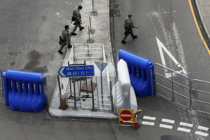 Riot police officers walk past a barricade as a second reading of a controversial national anthem law takes place in Hong Kong