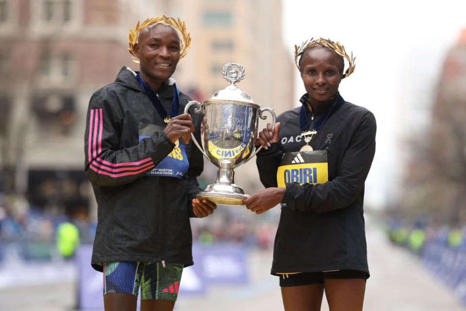 Evans Chebet (L) and Hellen Obiri (R) pose with the trophy on the finish line after winning the professional men’s and women’s division respectively during the 127th Boston Marathon on April 17, 2023. - Credit: Getty Images