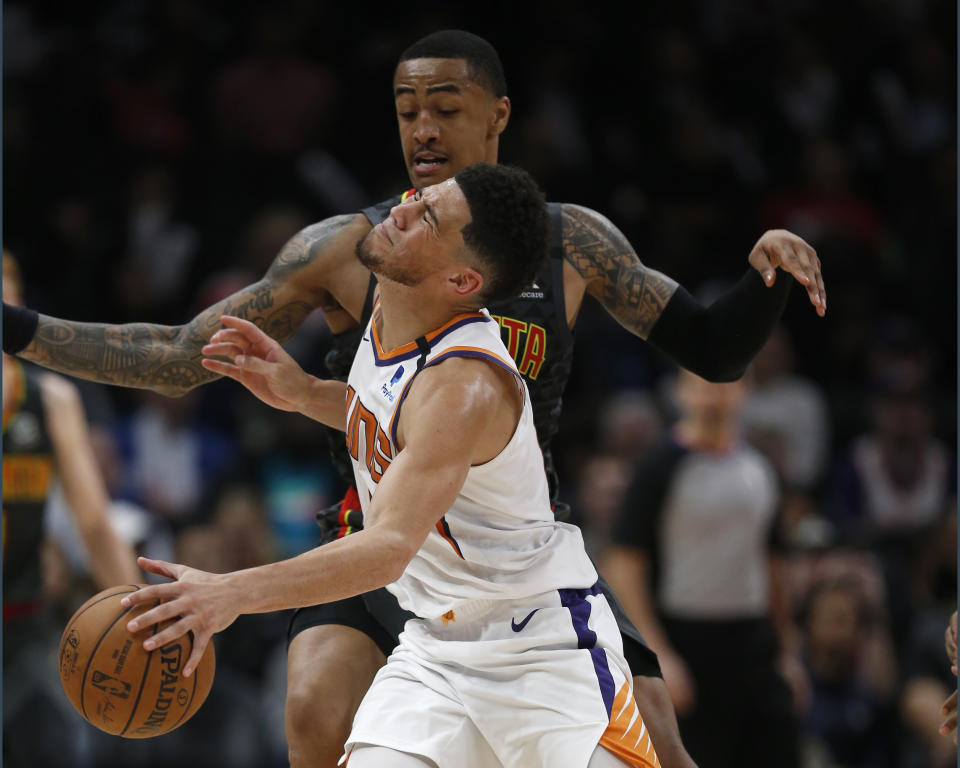 Phoenix Suns guard Devin Booker (1) is fouled by Atlanta Hawks forward John Collins (20) in the second half of an NBA basketball game Tuesday, Jan. 14, 2020, in Atlanta. The Hawks won 123-110. (AP Photo/John Bazemore)