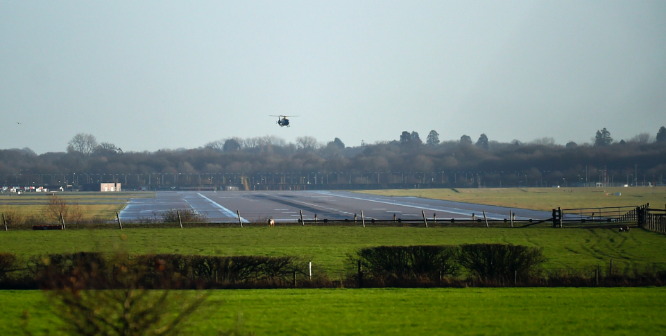 <em>The helicopter flies over the runway as the search continues for the drones and their operators (PA)</em>