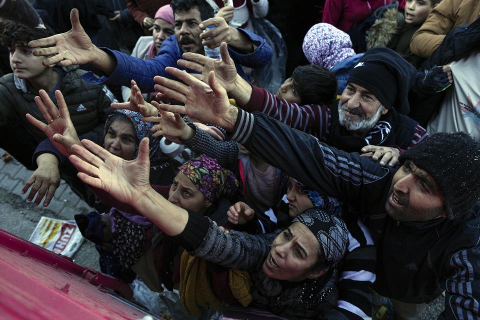 FILE - Volunteers distribute aid to people in Antakya, southern Turkey, on Feb. 8, 2023. A year after the devastating 7.8 magnitude earthquake struck southern Turkey and northwestern Syria, a massive rebuilding effort is still trudging along. The quake caused widespread destruction and the loss of over 59,000 lives. (AP Photo/Khalil Hamra, File)