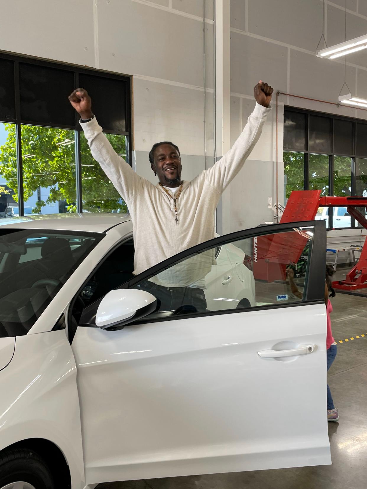 Isaac Taylor, a father of six who previously biked 16 miles roundtrip to work, celebrates after being given a free car.