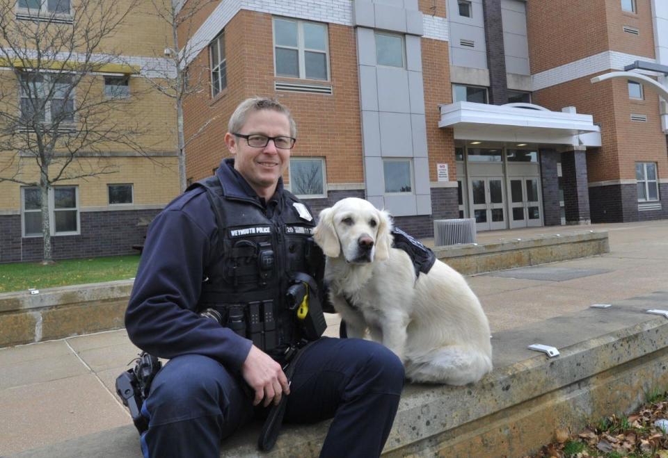 Charlee, a 3-year-old English cream golden retriever, with Weymouth School Resource Officer Ryan Hamacher.