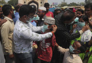 Indian social activists distribute masks to pedestrians at the landmark Charminar in Hyderabad, India, Thursday, March 5, 2020. A new virus first detected in China has infected more than 90,000 people globally and caused over 3,100 deaths. The World Health Organization has named the illness COVID-19, referring to its origin late last year and the coronavirus that causes it. (AP Photo/Mahesh Kumar A.)