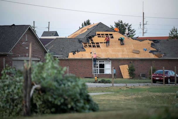 PHOTO: People work to repair damage done to a roof of building, June 25, 2023, after a tornado hit in Greenwood, Ind. (Clare Grant/USA Today Network)