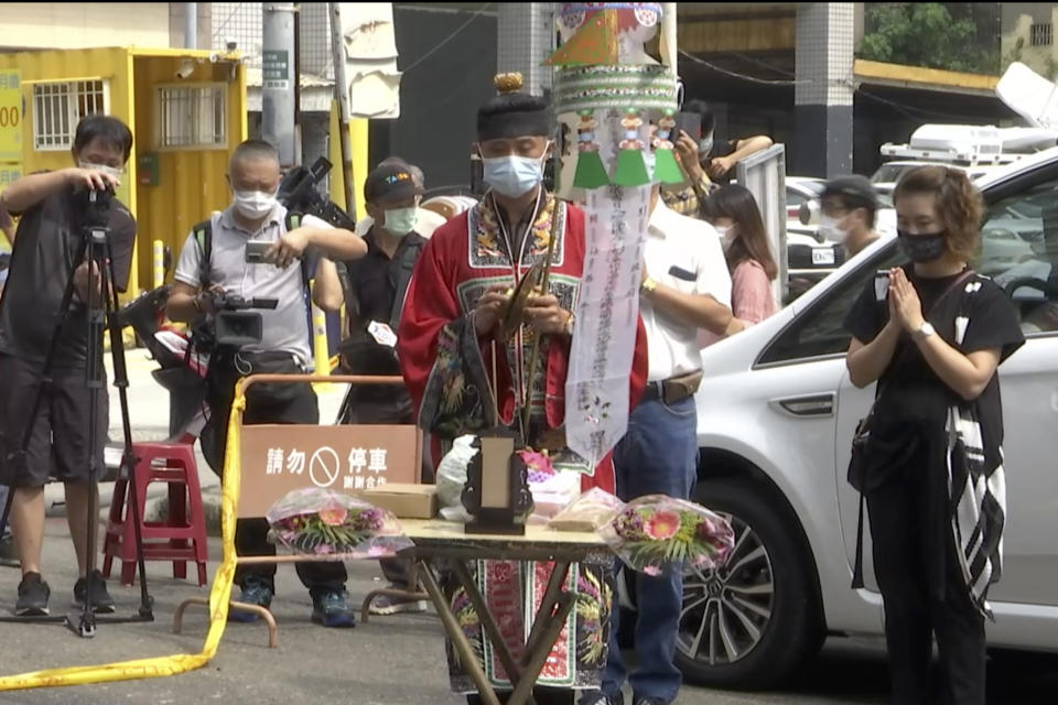 A Taoist priest performs rites outside the burnt building in Kaohsiung in southern Taiwan on Friday, Oct. 15, 2021. Taiwanese officials set up an independent commission Friday to investigate the conditions at a run-down building in the port city of Kaohsiung where a fire killed dozens while authorities scoured the blackened ruins for the cause of the blaze. (AP Photo/Wu Taijing)