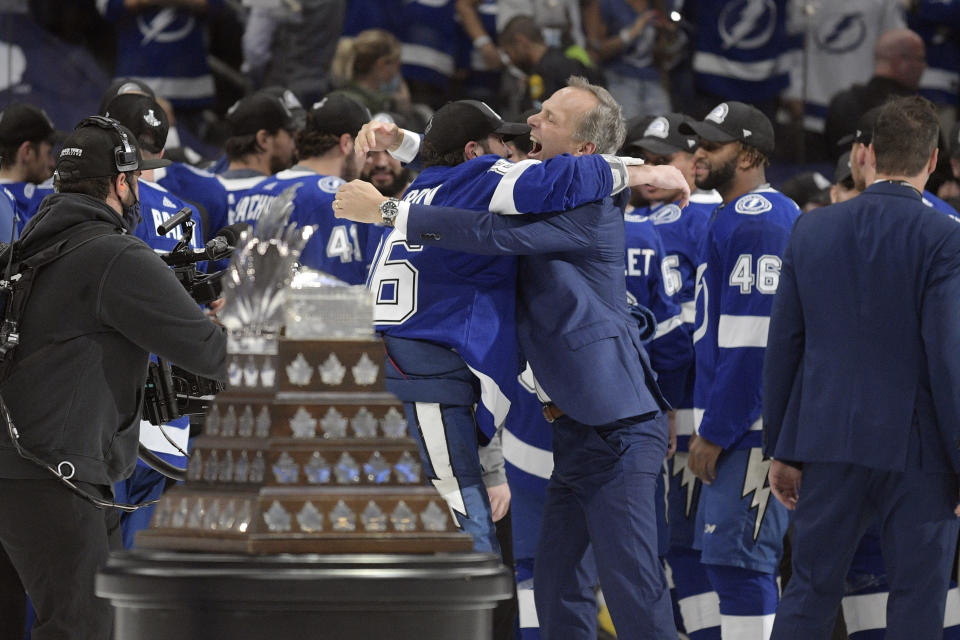 Tampa Bay Lightning head coach Jon Cooper is hugged by a player after the Lighting defeated the Montreal Canadiens in Game 5 of the NHL hockey Stanley Cup finals, Wednesday, July 7, 2021, in Tampa, Fla. (AP Photo/Phelan Ebenhack)