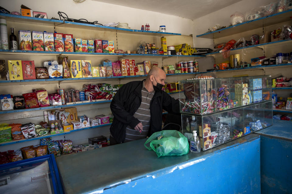 Kosovo Albanian Fadil Rama choses products from his shop to be sent to a Kosovo Serb Blagica Dicic a lonely 92-year old woman in a remote village of Vaganesh, Kosovo on Thursday, Nov. 19, 2020, abandoned by all her former ethnic Serb neighbors. Neighbor Blagica Dicic, is 92 and in failing health, in the remote ethnic Serb minority village in the mountains of eastern Kosovo but Fadil Rama comes from the other side of Kosovo’s bitter ethnic divide, being a member of Kosovo’s ethnic Albanian majority and Rama said he saw nothing strange in helping an elderly Serb. “I will never leave her on her own,” he said. (AP Photo/Visar Kryeziu)