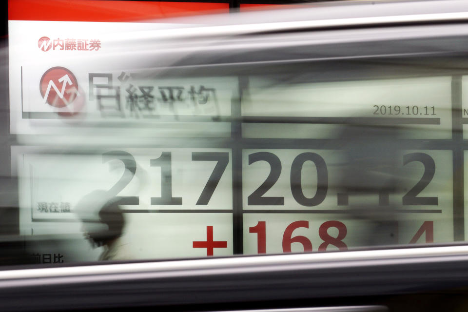 A woman walks past an electronic stock board showing Japan's Nikkei 225 index at a securities firm in Tokyo Friday, Oct. 11, 2019. Asian stock markets followed Wall Street higher Friday on optimism about U.S.-Chinese talks on ending a tariff war. (AP Photo/Eugene Hoshiko)