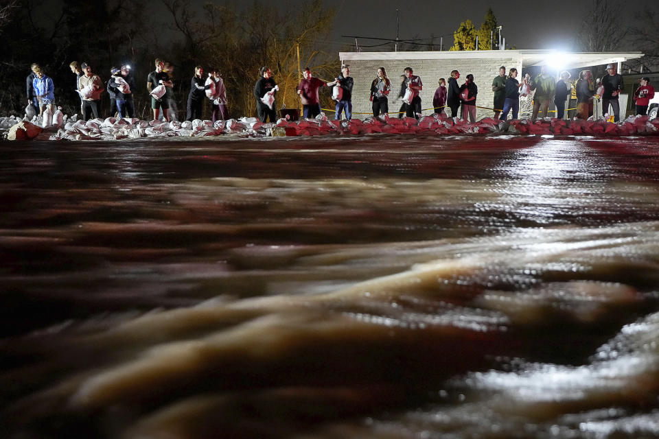 People work to protect homes into the night along 1700 South in Salt Lake City from the rising flow of Emigration Creek through Wasatch Hollow Park on Wednesday, April 12, 2023. As rapid snowmelt and possible April showers stoke fears of heavy flooding in the Northern Plains, state officials are announcing flood response plans, and residents are assembling thousands — if not hundreds of thousands — of sandbags to combat floods themselves. (Francisco Kjolseth/The Salt Lake Tribune via AP)