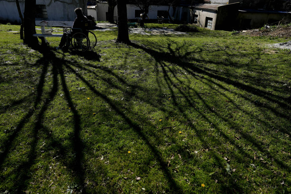 Valentin Faijoo sits behind the San Jose Home for seniors where he lives, next to his caged birds on the bench in Tandil, Argentina, Wednesday, Sept. 15, 2021. Faijoo was allowed to take his pets to the residence during the COVID-19 pandemic lockdown and said it changed everything for good. (AP Photo/Natacha Pisarenko)