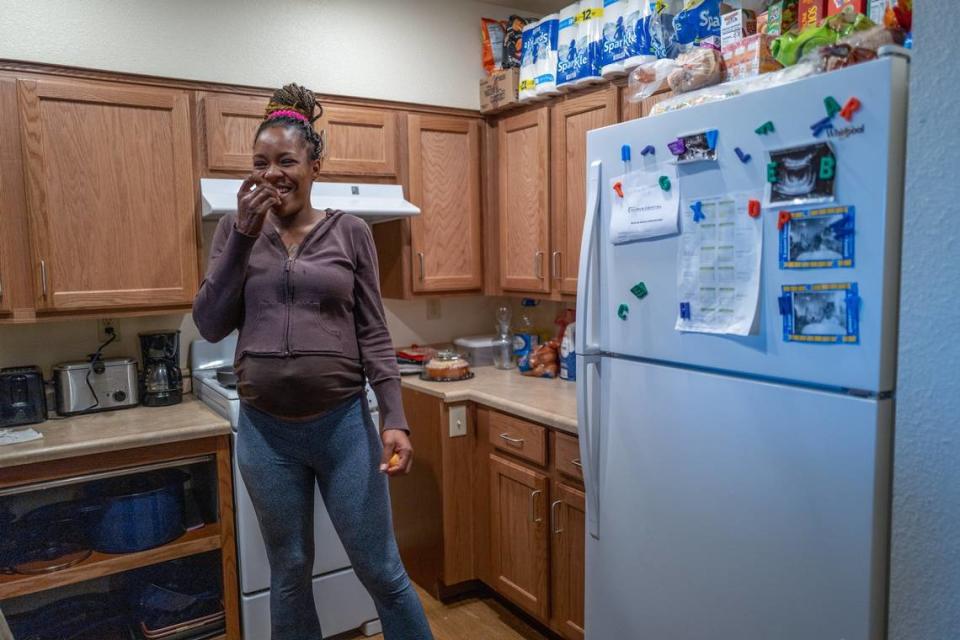 Yolo Basic Income program recipient Marquisha Brown eats an orange in the kitchen of her low-income apartment on April 5, 2023. A sonogram from a prenatal ultrasound for the baby girl she is expecting in July is posted on the refrigerator. “Without YOBI, I would not have been able to move and have a stable place,” said Brown.