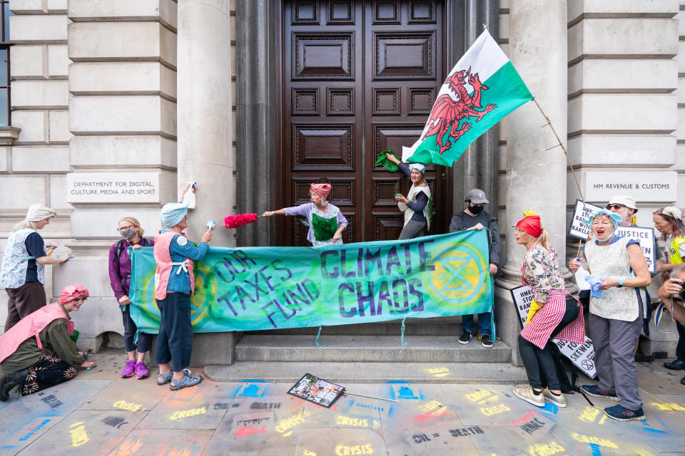 Activists from Extinction Rebellion dressed as cleaners hold a protest outside the offices of HM Revenue and Customs (HMRC) in Whitehall, Westminster, central London. Picture date: Tuesday August 24, 2021.