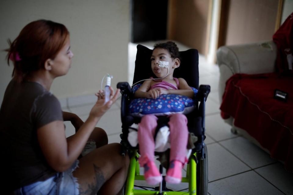 Rosana Vieira Alves, feeds her two-year-old daughter Luana Vieira, who was born with microcephaly, at their house in Olinda, Brazil (Reuters)