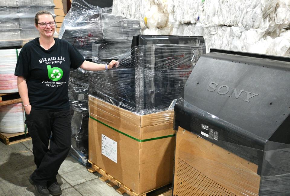 Samantha Buterbaugh next to pallets of old televisions ready for recycling or hazardous waste disposal at Biz Aid Recycling on Darling Drive.