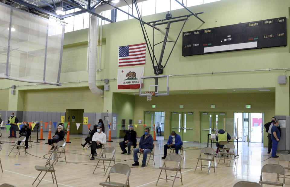 Los Angeles Unified School District employees wait in the school gym before getting their first dose of the Moderna vaccine, as LAUSD's first vaccination site opened at the Roybal Learning Center, Wednesday, Feb. 17, 2021, in Los Angeles. Superintendent Austin Beutner was there in the morning to meet with the vaccination team and the first district employees to receive their vaccines at this site. (Dean Musgrove/The Orange County Register/SCNG via AP)