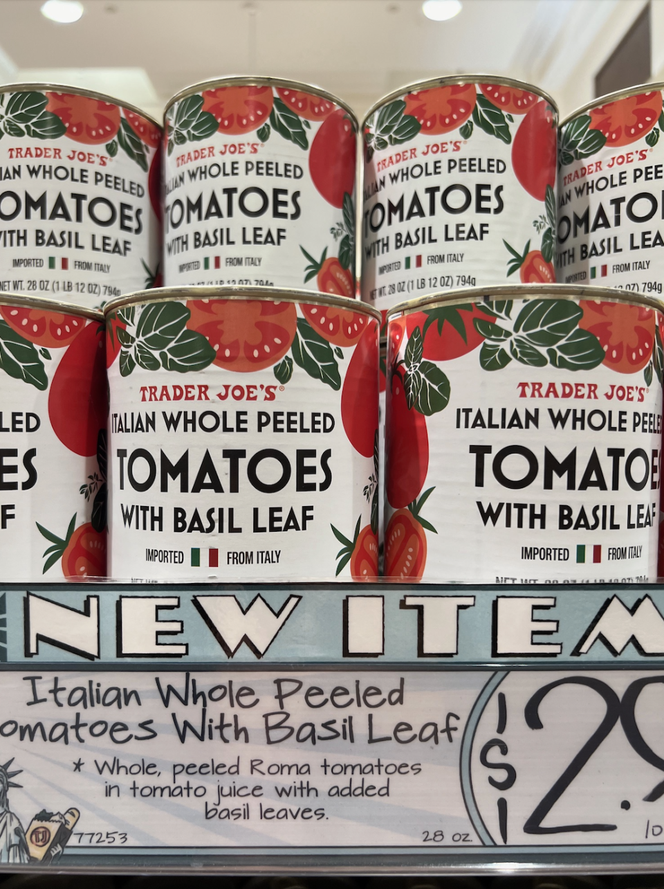 Cans of Trader Joe's Italian Whole Peeled Tomatoes with Basil Leaf are on display, with a price sign showing $2.99 for a 28 oz can