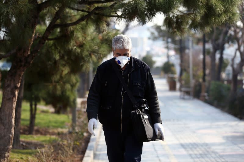 An Iranian man wears a protective mask to prevent contracting coronavirus, as he walks on a street in Tehran