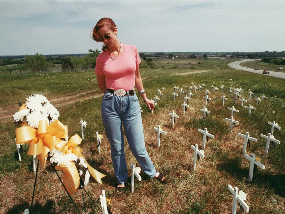 A woman stands among crosses signifying the loss of life from the Waco Siege.