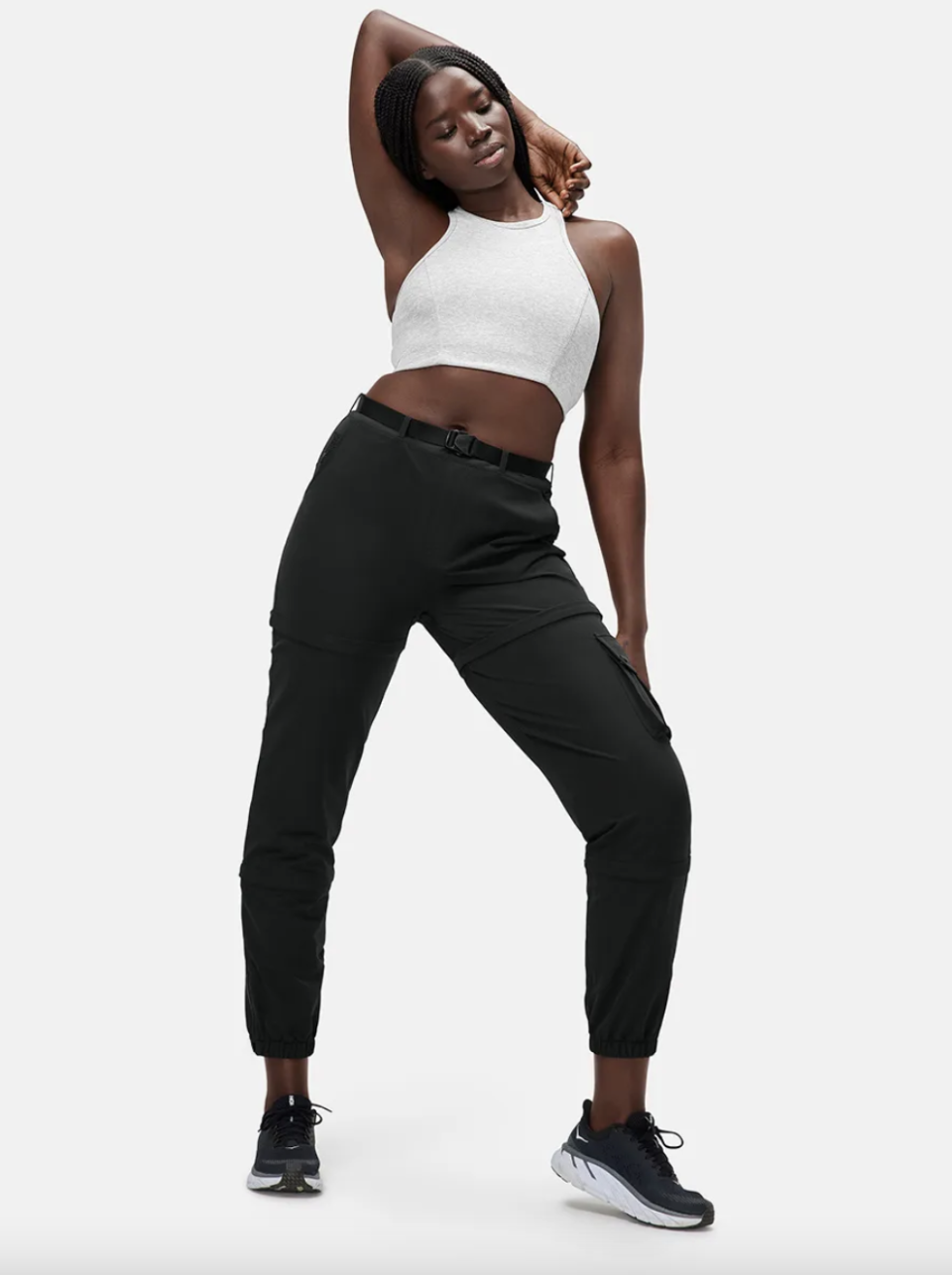 black model wearing white crop top and black Outdoor Voices Rectrek Zip-Off Pants with black sneakers