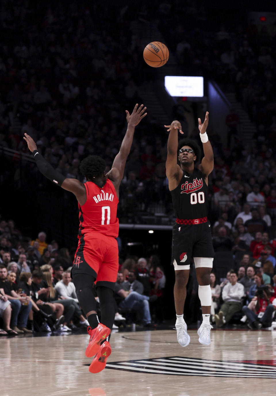 Portland Trail Blazers guard Scoot Henderson, right, shoots over Houston Rockets guard Aaron Holiday, left, during the first half of an NBA basketball game Friday, April 12, 2024, in Portland, Ore. (AP Photo/Howard Lao)