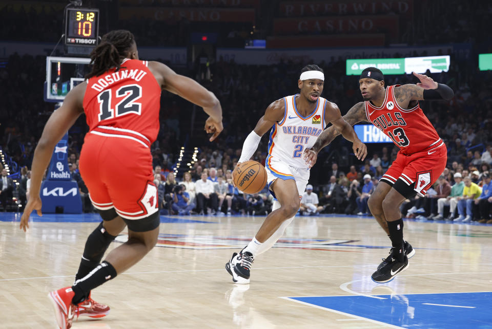 Nov 22, 2023; Oklahoma City, Oklahoma, USA; Oklahoma City Thunder guard Shai Gilgeous-Alexander (2) drives between Chicago Bulls guard <a class="link " href="https://sports.yahoo.com/nba/players/6580" data-i13n="sec:content-canvas;subsec:anchor_text;elm:context_link" data-ylk="slk:Ayo Dosunmu;sec:content-canvas;subsec:anchor_text;elm:context_link;itc:0">Ayo Dosunmu</a> (12) and forward <a class="link " href="https://sports.yahoo.com/nba/players/5893" data-i13n="sec:content-canvas;subsec:anchor_text;elm:context_link" data-ylk="slk:Torrey Craig;sec:content-canvas;subsec:anchor_text;elm:context_link;itc:0">Torrey Craig</a> (13) during the first quarter at Paycom Center. Mandatory Credit: Alonzo Adams-USA TODAY Sports