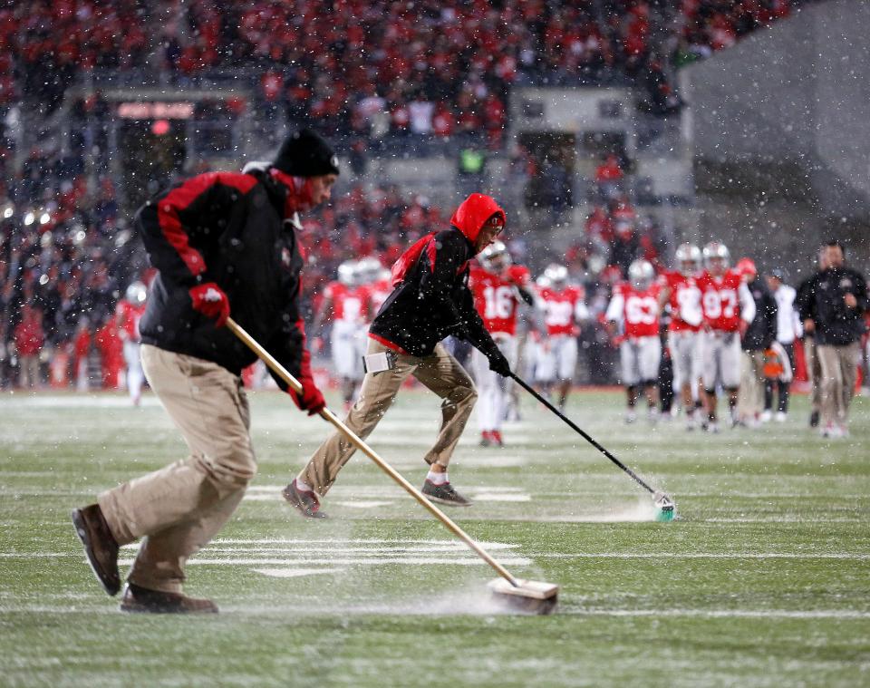 Ohio State Buckeyes ground crews clear the snow from the yard lines after the third quarter of the Ohio State Buckeyes and Indiana Hoosiers college football game at Ohio Stadium in Columbus, Ohio on November 23, 2013.  (Dispatch photo by Kyle Robertson) 