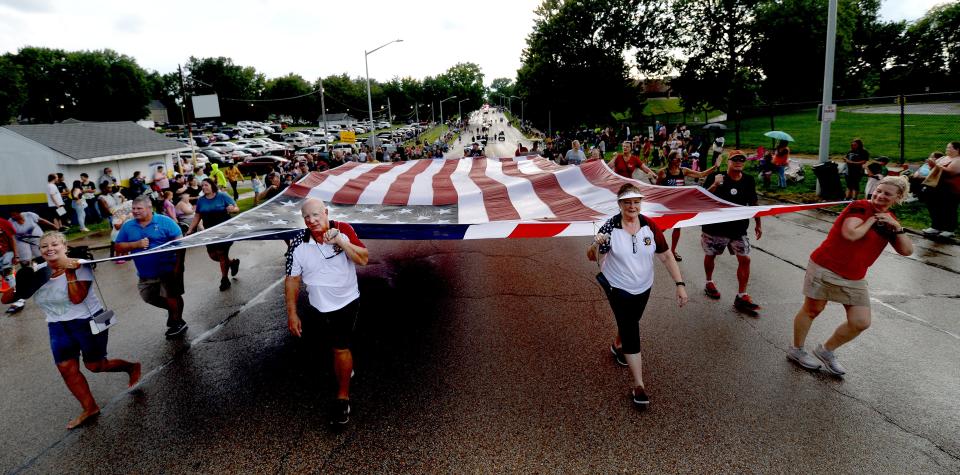 A large American flag leads most of the 2022 Illinois State Fair Twilight Parade down Sangamon Ave towards the fair ground Thursday August 11, 2022.