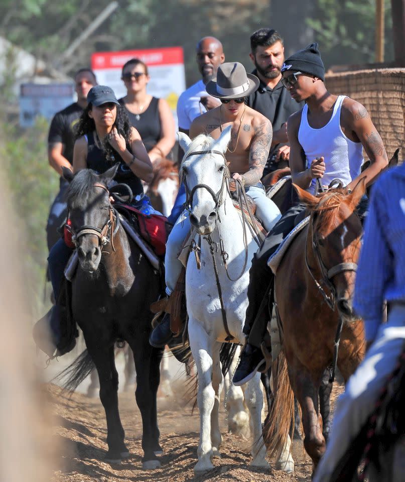 Doesn’t everyone take off their shirt — and wear a fedora — when they go horseback riding? Yee-haw! (Photo: Splash News)