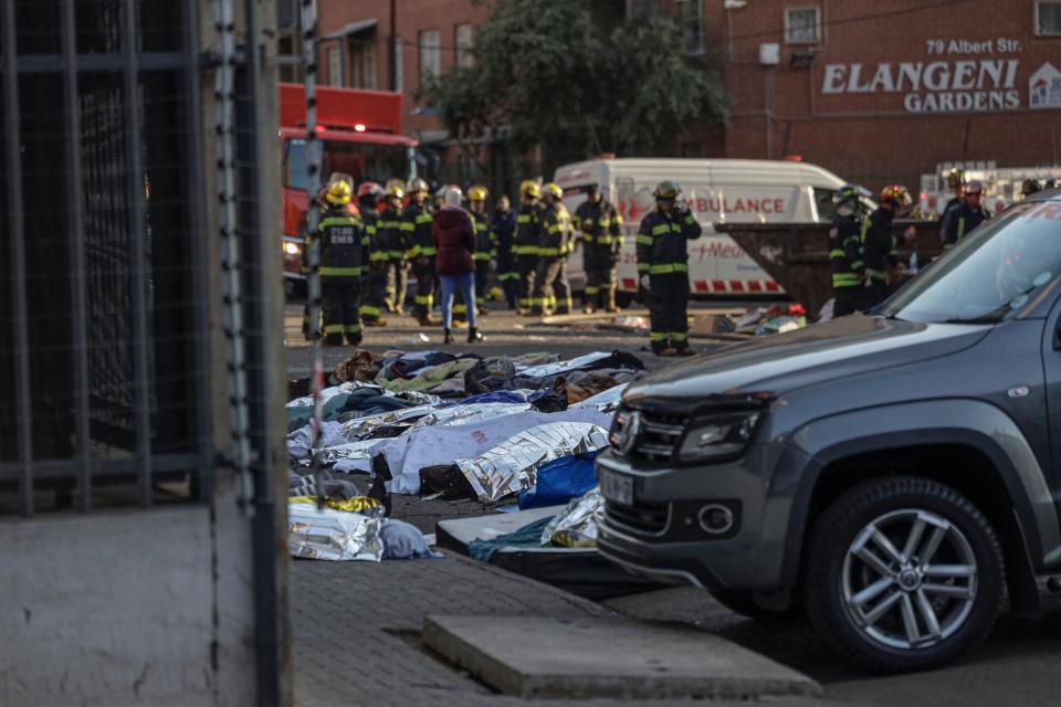 Bodies covered in blankets and sheets are seen at the scene of a fire in Johannesburg on 31 August 2023 (AFP via Getty Images)