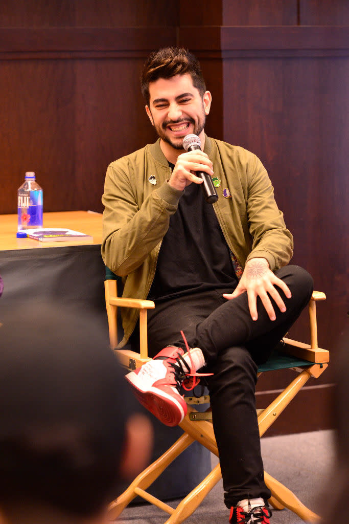 Gabriel smiling and speaking into a microphone during a panel discussion. He is seated