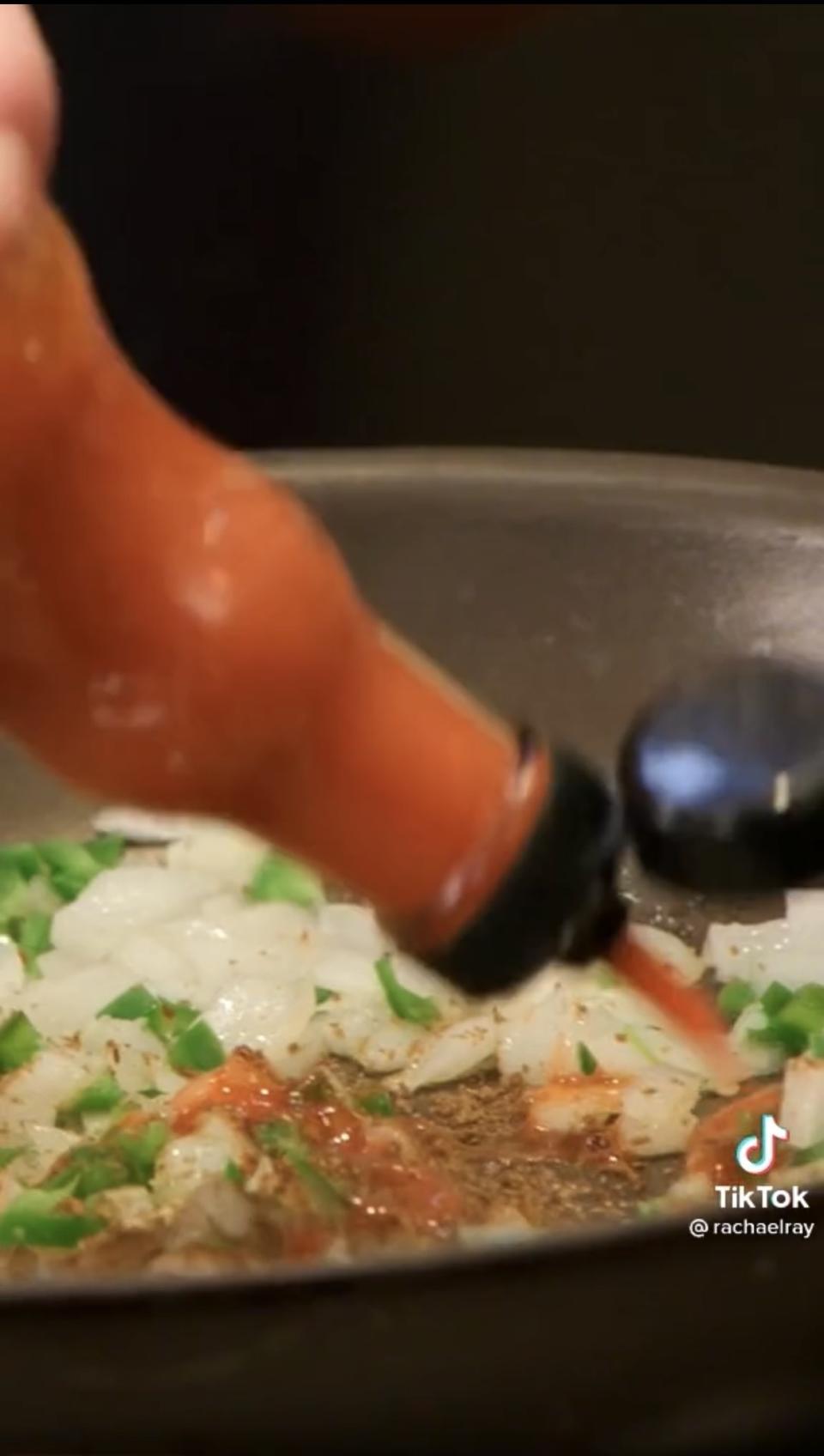 Rachel squirting hot sauce into the skillet