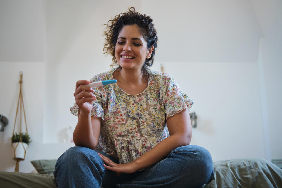 woman gleefully looking at her pregnancy test