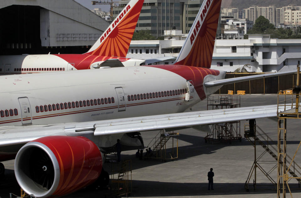 A man stands under a parked Air India aircraft at the Chhatrapati Shivaji international airport in Mumbai, India, Friday, May 11, 2012. Hundreds of passengers have been stranded in India after Air India canceled around 20 international flights due to a strike by pilots. (AP Photo/Rajanish Kakade)