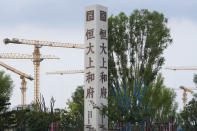 Construction cranes stand near the Evergrande's name and logo at its new housing development in Beijing, Wednesday, Sept. 15, 2021. One of China's biggest real estate developers is struggling to avoid defaulting on billions of dollars of debt, prompting concern about the broader economic impact and protests by apartment buyers about delays in completing projects. Rating agencies say Evergrande Group appears likely to be unable to repay all of the 572 billion yuan ($89 billion) it owes banks and other bondholders. That might jolt financial markets, but analysts say Beijing is likely to step in to prevent wider damage. (AP Photo/Andy Wong)